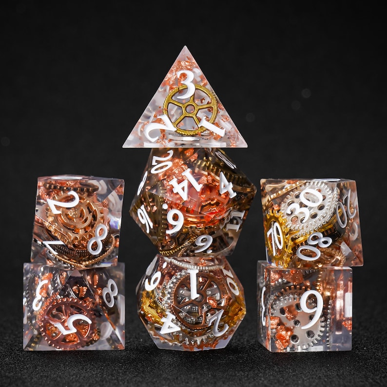 May include: A set of seven polyhedral dice with a steampunk theme. The dice are clear with copper, gold, and silver gears and white numbering. The set includes a D4, D6, D8, D10, D12, D20, and a D%.