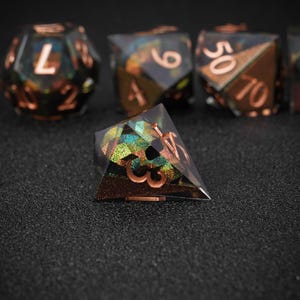 Peut inclure: Un ensemble de d&eacute;s poly&eacute;driques au design unique. Les d&eacute;s ont un corps en r&eacute;sine transparente avec des couleurs iris&eacute;es et des chiffres cuivr&eacute;s. Les d&eacute;s sont con&ccedil;us pour les jeux de soci&eacute;t&eacute;.