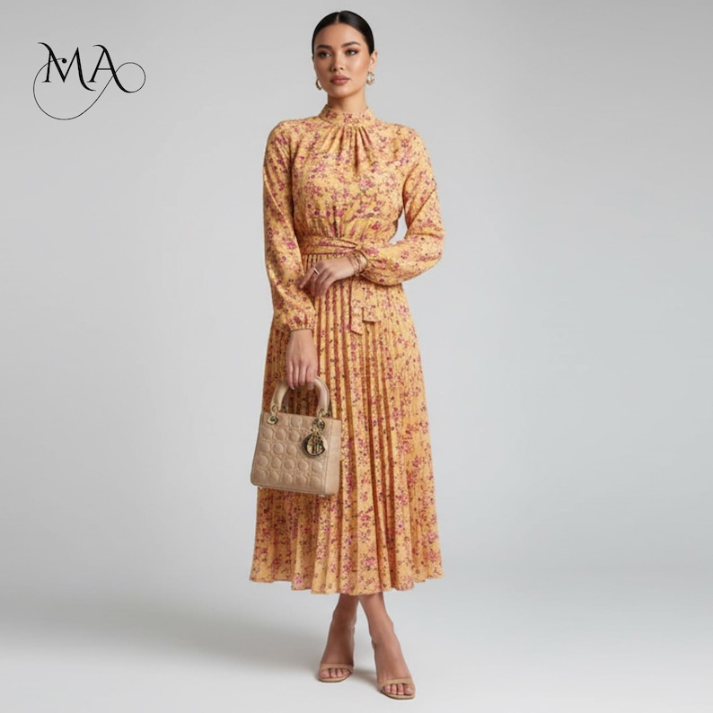 Puede incluir: Un vestido amarillo de manga larga con estampado floral y falda plisada. El vestido presenta un cuello alto, una cintura ce&ntilde;ida y un cintur&oacute;n a juego. Un bolso beige y sandalias completan el look. El vestido es adecuado para ocasiones formales.