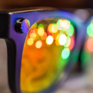 May include: A white ceramic mug with a black handle and the text "But First, Coffee" in a bold, black font. The mug is set against a blurred background, suggesting a cozy setting. The mug appears to be approximately 4 inches tall.