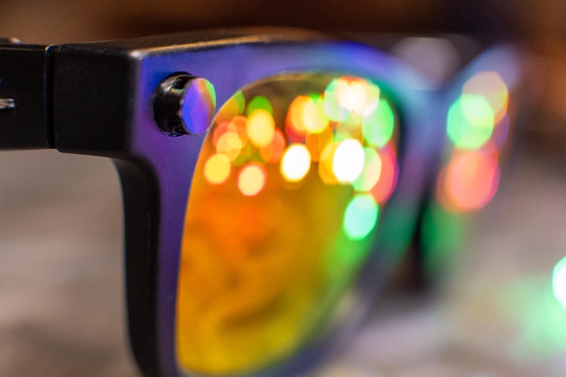 May include: A white ceramic mug with a black handle and the text "But First, Coffee" in a bold, black font. The mug is set against a blurred background, suggesting a cozy setting. The mug appears to be approximately 4 inches tall.