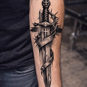 May include: A detailed black and grey tattoo of a sword with a cross-shaped hilt and a cross on the blade. A crown of thorns and a banner with the numbers "1925" are wrapped around the sword. The tattoo is on a person's forearm.