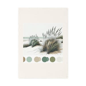 Op de afbeelding: Een rechthoekige, crèmekleurige keukendoek met een aquarelillustratie van helmgras op een zandduin. Een kleurenpalet van groen, bruin en beige stippen wordt onder de afbeelding weergegeven. De handdoek is gemaakt van een zacht, absorberend materiaal.
