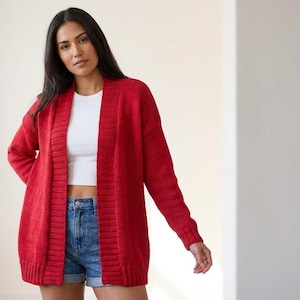 May include: A bright red cardigan with long sleeves. The open-front design is worn with a white top and denim shorts. The sweater is made of a soft, knitted material, ideal for layering.