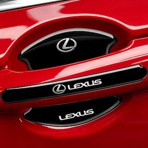 Puede incluir: Primer plano de una puerta de coche roja con detalles negros. El logotipo de Lexus en plata y la palabra "LEXUS" en letras blancas son visibles. La zona del tirador de la puerta tiene un acabado brillante.