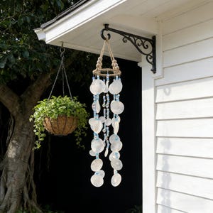 May include: A white ceramic mug with a black handle and the text "But First, Coffee" in a bold, black font. The mug is set against a blurred background, suggesting a cozy setting. The mug appears to be approximately 4 inches tall.