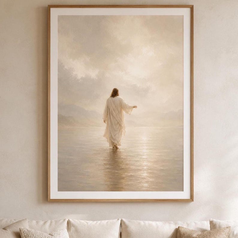 May include: A framed wall art print depicting a figure in a long, light-colored robe walking across a calm, reflective body of water toward a bright, hazy horizon under a cloudy sky, rendered in soft, warm, monochromatic beige and cream tones.