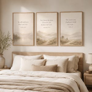 May include: Three rectangular wall art prints in light wood frames featuring beige landscape scenes with misty mountains and water. Each print displays religious text: Psalm 46:10, Jeremiah 29:11, and Psalm 23, written in a simple dark font.