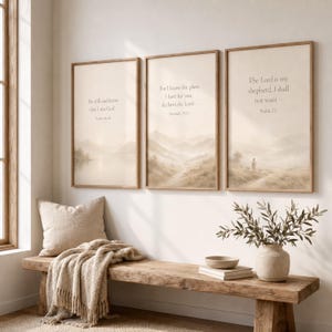 May include: Three vertical framed wall art prints featuring beige landscape illustrations with religious text. The left print reads Psalm 46:10, the center Jeremiah 29:11, and the right Psalm 23. Each print is encased in a light wood frame.