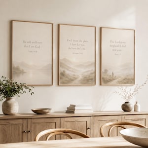 May include: Three vertical framed wall art prints with beige and tan watercolor landscapes. The left print reads Be still and know that I am God - Psalm 46:10. The center reads For I know the plans I have for you, declares the Lord - Jeremiah 29:11. The right reads The Lord is my shepherd; I shall not want - Psalm 23.