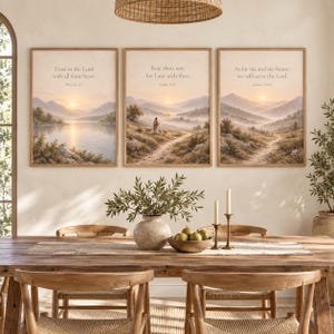 Op de afbeelding: Een set van drie ingelijste wandkunstprints met landschappen in zachte, gedempte kleuren. Elke print toont een bijbelvers in zwarte tekst: Trust in the Lord, Fear thou not en As for me and my house, we will serve the Lord.