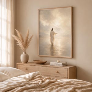 May include: A framed wall art print depicting a figure in a long white robe walking across a calm body of water toward a bright, cloudy horizon. The scene is rendered in soft, neutral tones of beige, cream, and light gold, creating a serene atmosphere.