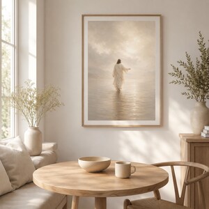 May include: A framed wall art print featuring a figure in a long white robe walking across a calm, reflective body of water toward a bright, hazy horizon. The scene is rendered in soft, neutral beige and cream tones with a glowing light effect.