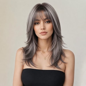 May include: A woman with long, layered gray wig with bangs. The wig has a natural-looking style and is worn with a black strapless top and a gold necklace.