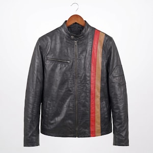 Puede incluir: Una chaqueta de cuero negro con cuello alzado y botón a presión, cremallera frontal completa y dos franjas verticales en rojo y beige en el lado izquierdo. Incluye un bolsillo en el pecho con cremallera y un pequeño bolsillo en la manga.