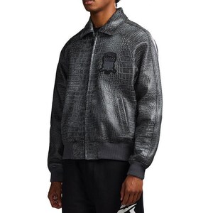 May include: A charcoal gray bomber jacket featuring a textured crocodile skin pattern throughout. The jacket includes a front zipper closure, a pointed collar, ribbed cuffs and hem, and a dark circular patch on the left chest with text.