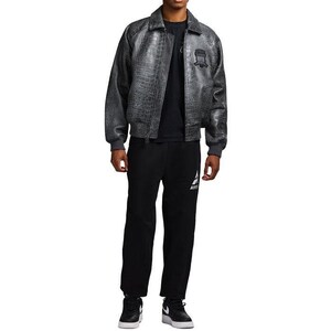 May include: A charcoal gray bomber jacket with a textured crocodile skin pattern, featuring a pointed collar, ribbed cuffs, and a dark embroidered patch on the chest. It is worn over a plain black t-shirt, black sweatpants, and black and white sneakers.