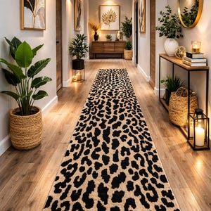 Könnte beinhalten: Ein langer, rechteckiger Flurläufer mit einem sich wiederholenden Leopardenmuster in Schwarz und Beige. Der Teppich liegt mittig auf einem hellen Holzboden und erstreckt sich vom Vordergrund bis zu einer hölzernen Konsole im Hintergrund.