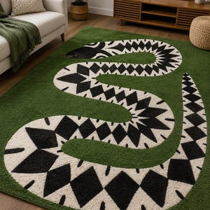 May include: A rectangular area rug featuring a deep green background with a large, stylised snake motif. The snake is depicted in a winding, S-shaped pattern, rendered in contrasting black and cream diamond shapes with a textured, tufted pile finish.