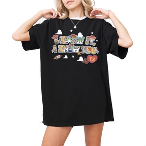 May include: A black short-sleeved t-shirt featuring a graphic print with the text I KNEW IT, I KNEW YOU. The letters are filled with patterns of cartoon characters, accompanied by small illustrations of a rocket, cowboy hats, boots, and a heart.