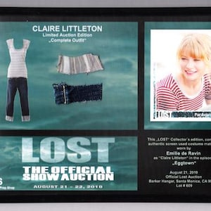 May include: Framed display featuring a "LOST" collector's edition. Includes a photo of Emilie de Ravin, a complete outfit worn by Claire Littleton, and show details. The text reads "THE OFFICIAL SHOW AUCTION".
