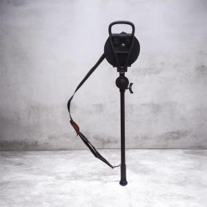 May include: A dark brown, adjustable walking stick with a built-in seat. The seat is round and black, with a handle at the top. A black and brown strap is attached to the seat. The walking stick is designed to provide support and a place to sit.