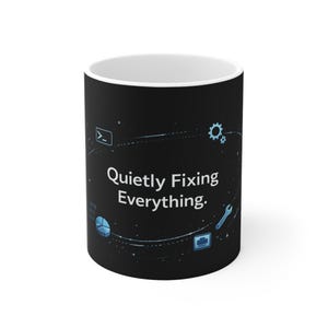 May include: A white ceramic mug with a black exterior. The mug features the text "Quietly Fixing Everything" in white, along with small blue tech-related icons and a dotted line design.