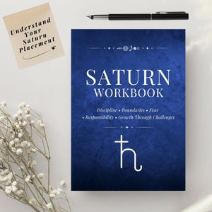 以下が含まれることがあります： 白文字と土星のシンボルが入った、ネイビーブルーの「Saturn Workbook」。ワークブックには「Discipline, Boundaries, Fear, Responsibility, Growth Through Challenges」というテキストが含まれています。「Understand Your Saturn Placement」と書かれた付箋。