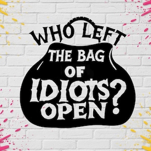 Op de afbeelding: Een zwart grafisch ontwerp met de witte tekst "WHO LEFT THE BAG OF IDIOTS OPEN?" in de vorm van een handtas. Het ontwerp is geplaatst tegen een witte bakstenen muur met gele en roze verfspatten in de vier hoeken van de afbeelding.