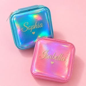 May include: Two square, iridescent jewelry cases, one blue and one pink, with gold lettering. The blue case says "Sophia" and the pink case says "Isabella", each with a small heart. Both cases have a zipper closure.