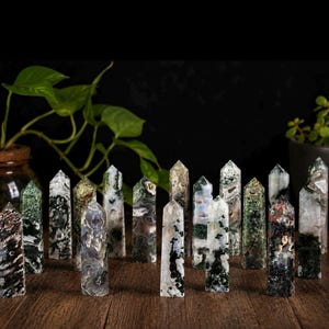 May include: A collection of sixteen polished stone points arranged in a group. Each point features unique patterns of mossy green, translucent white, and dark brown inclusions within the mineral structure, standing upright with a faceted top.