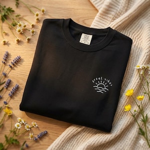 May include: A white ceramic mug with a black handle and the text "But First, Coffee" in a handwritten style. The mug is on a white surface. The mug is 10 cm tall.