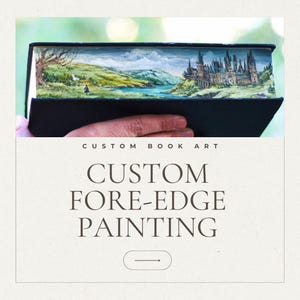 Könnte beinhalten: Ein individuelles Buch mit einem bemalten Buchschnitt, der eine Landschaft mit einer Burg, einem Fluss und Bäumen zeigt. Das Buch ist geöffnet und zeigt das Kunstwerk. Der Text auf dem Bild lautet "CUSTOM BOOK ART" und "CUSTOM FORE-EDGE PAINTING".