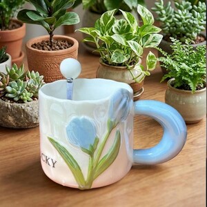 Puede incluir: Un juego de tres tazas de cerámica con un acabado mate moteado. Las tazas son en tonos crema, gris claro y gris oscuro. Cada taza tiene un diseño simple y minimalista y un asa redondeada.