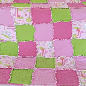 May include: A pink and green patchwork quilt with a ruffled edge. The quilt is made of squares of fabric with different patterns, including a giraffe print.