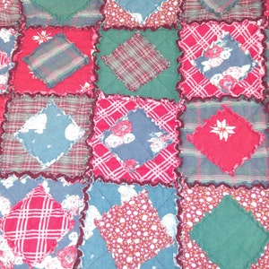 May include: A patchwork quilt with a variety of red, green, and blue fabrics. The quilt is made up of squares with different patterns, including plaid, floral, and geometric designs.