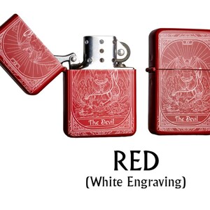 May include: Red lighter with white engraving featuring a detailed illustration of a devil figure. The lighter is shown open and closed, with the text "The Devil" on the front. The word "RED" is displayed below the lighters.