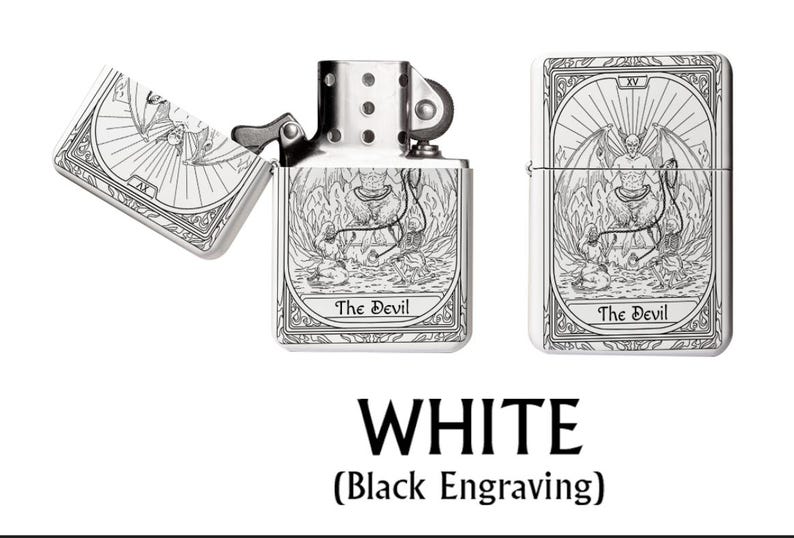 May include: A white metal lighter with a black engraved tarot card design featuring "The Devil" on the front and back. The lighter is shown open and closed, with the text "WHITE (Black Engraving)" below.