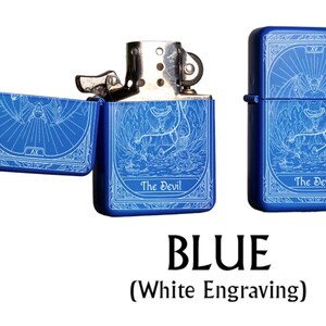 May include: Blue metal lighter with white engraving of a tarot card design. The lighter is shown open and closed, with the text "The Devil" on the front. The word "BLUE" is displayed below the lighters.