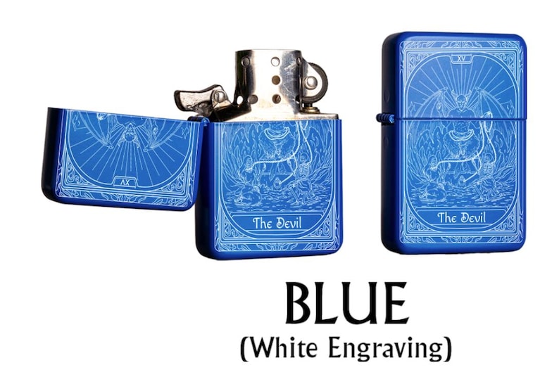 May include: Blue metal lighter with white engraving of a tarot card design. The lighter is shown open and closed, with the text "The Devil" on the front. The word "BLUE" is displayed below the lighters.