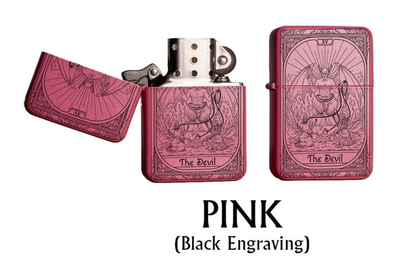May include: Pink metal lighter with a black engraved tarot card design featuring "The Devil" on the front and back. The lighter is shown open and closed. The text "PINK" and "(Black Engraving)" are at the bottom.