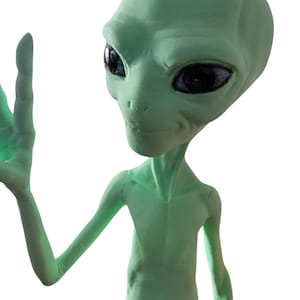 Op de afbeelding: Een lichtgroene alienfiguur met grote zwarte ogen en een slank postuur. De alien heft zijn rechterhand op, alsof hij zwaait. De figuur heeft een gladde textuur en staat tegen een effen witte achtergrond.