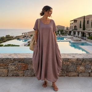 Peut inclure: Une robe longue mauve à la coupe ample, dotée de manches courtes, d'une encolure ronde et d'une silhouette fluide et décontractée arrivant aux chevilles. Le vêtement présente un design uni simple avec des poches latérales et une texture douce.