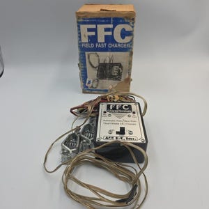 May include: An FFC Field Fast Charger with a box and charger unit. The box is blue and tan with the text "FFC FIELD FAST CHARGER". The charger unit is black and silver with the text "FFC Charge System".