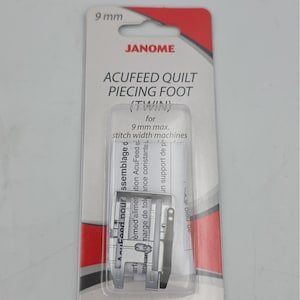 May include: A Janome Acufeed Quilt Piecing Foot (Twin) for 9 mm max. stitch width machines. The silver metal sewing machine accessory is enclosed in a clear plastic blister pack on a white and red cardboard backing with black text.