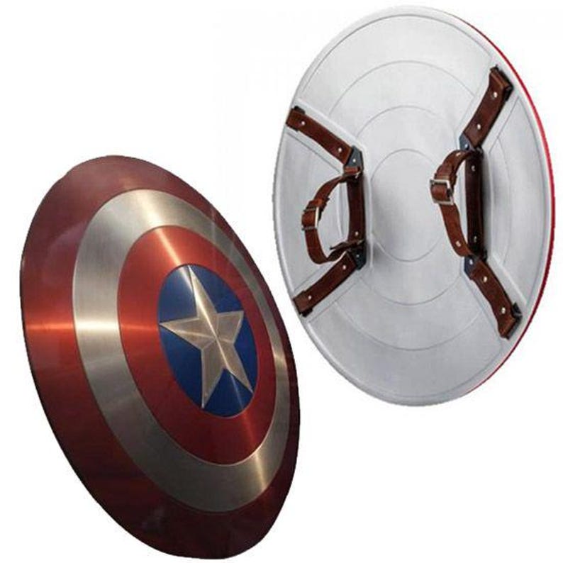 K&ouml;nnte beinhalten: Zwei Captain America Schilde. Ein Schild ist angewinkelt und zeigt ein rotes, silbernes und blaues Design mit einem Stern. Das andere Schild zeigt die R&uuml;ckseite mit braunen Lederriemen und einer wei&szlig;en Oberfl&auml;che.