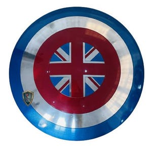 May include: A round shield with a blue, silver, and red color scheme. The shield features a Union Jack design at the center, with a blue outer ring and a silver inner ring. A small emblem is visible on the left side.
