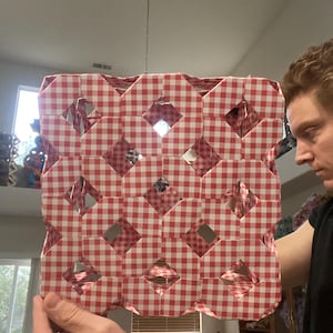 May include: A red and white gingham patterned lampshade with a geometric design. The lampshade is held up by a chain and has mirrored accents. The design features diamond-shaped cutouts.