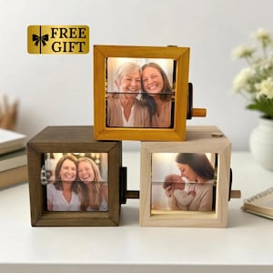 May include: Three wooden photo cubes with rotating images. One cube is golden yellow, another is dark brown, and the third is light wood. Each cube displays a different family photo. A gold label with the text "FREE GIFT" is in the upper left corner.