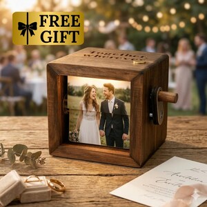 May include: A wooden photo cube with a picture of a couple in a field. The cube has a crank on the side and the words "Together wherever" engraved on top. A gold-colored "FREE GIFT" sticker is in the upper left corner.